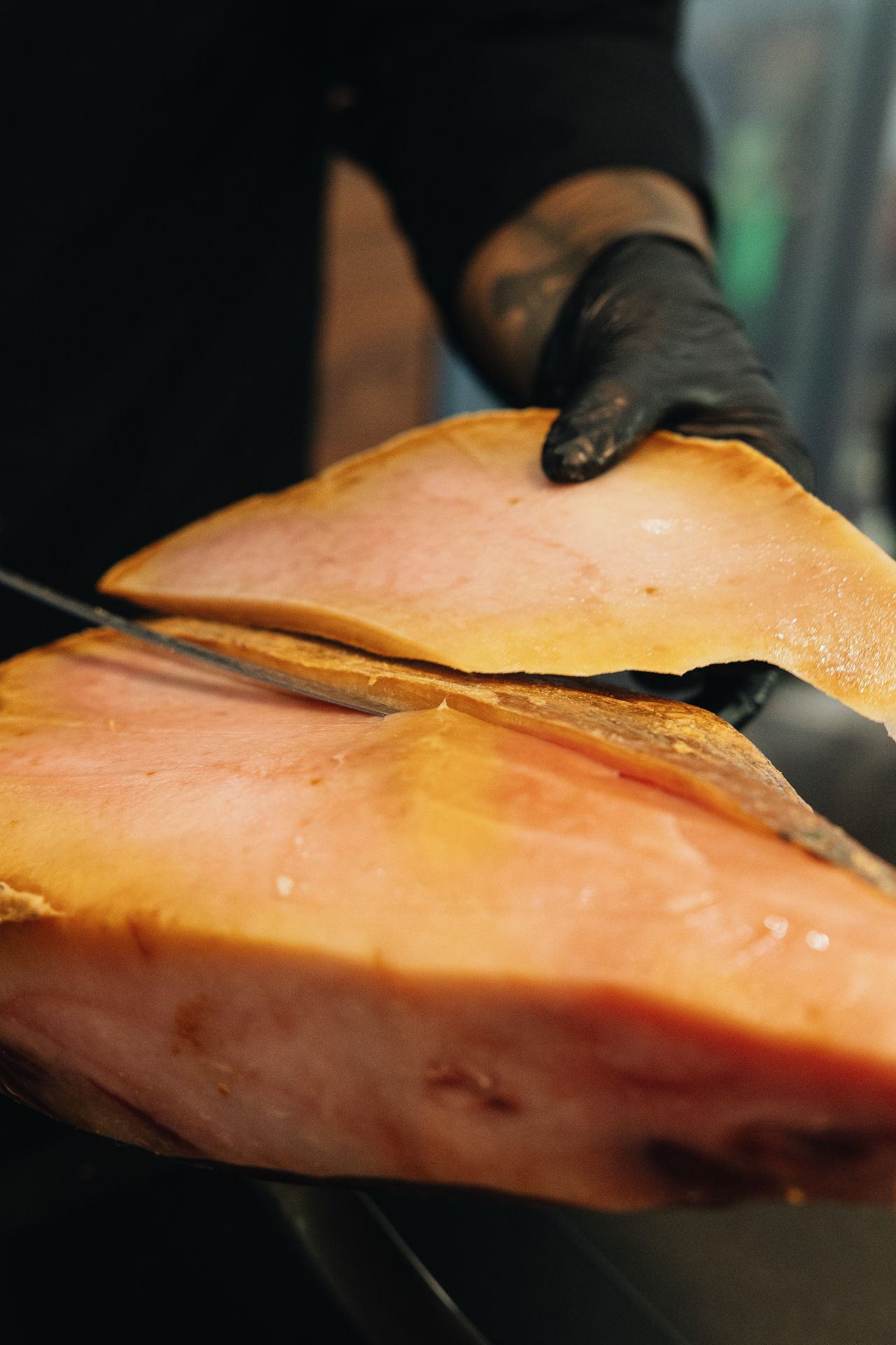 Cortador profesional realizando corte de jamón con cuchillo profesional en jamonero profesional abellan con sistema basculante patentado y sistema giratorio