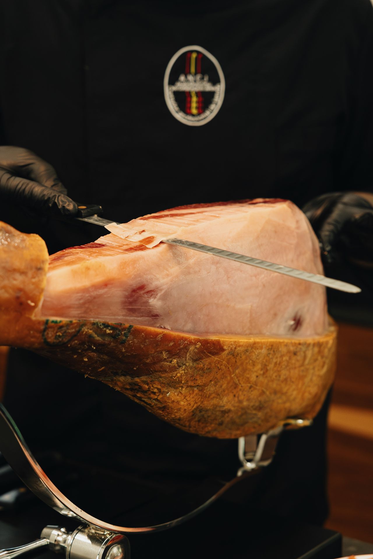 Cortador profesional realizando corte de jamón con cuchillo profesional en jamonero profesional abellan con sistema basculante patentado y sistema giratorio