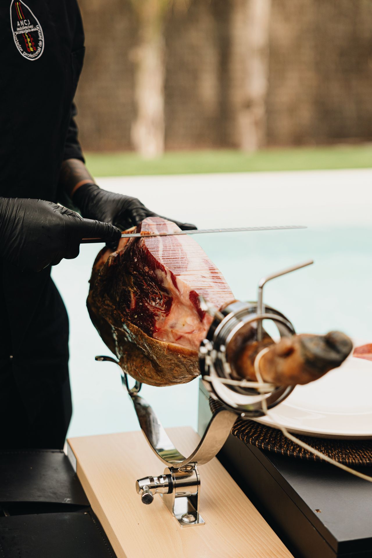 Cortador profesional realizando corte de jamón con cuchillo profesional en jamonero profesional abellan con sistema basculante patentado y sistema giratorio