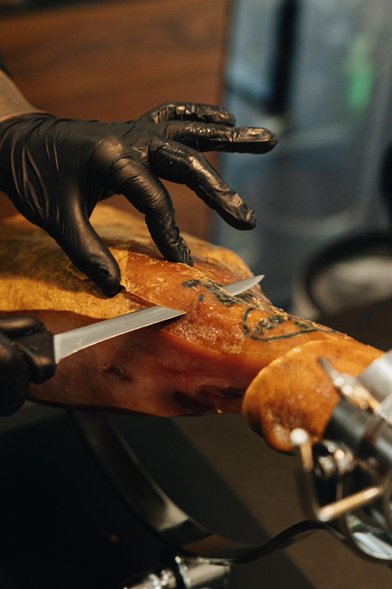 Cortador profesional realizando corte de jamón con cuchillo profesional en jamonero profesional abellan con sistema basculante patentado y sistema giratorio